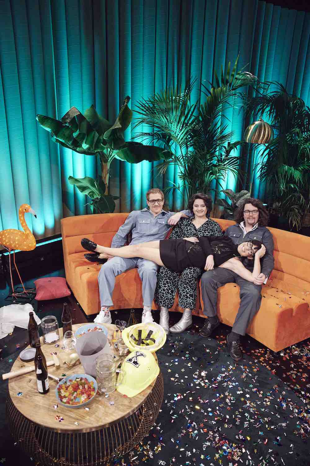 Manu, Maria, Flori auf oranger Couch, Eva liegt quer drauf.